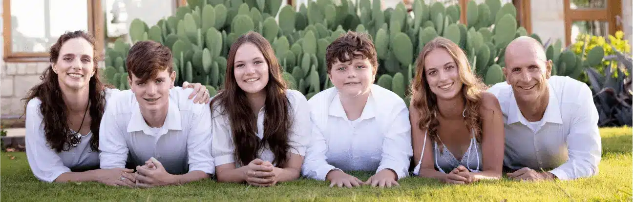 Family of six lying on grass, smiling together