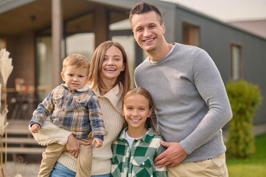 Smiling family of four standing outdoors.