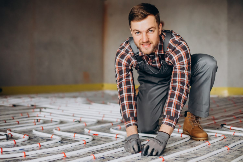 A man installing an underfloor heating system, representing energy-efficient home upgrades.