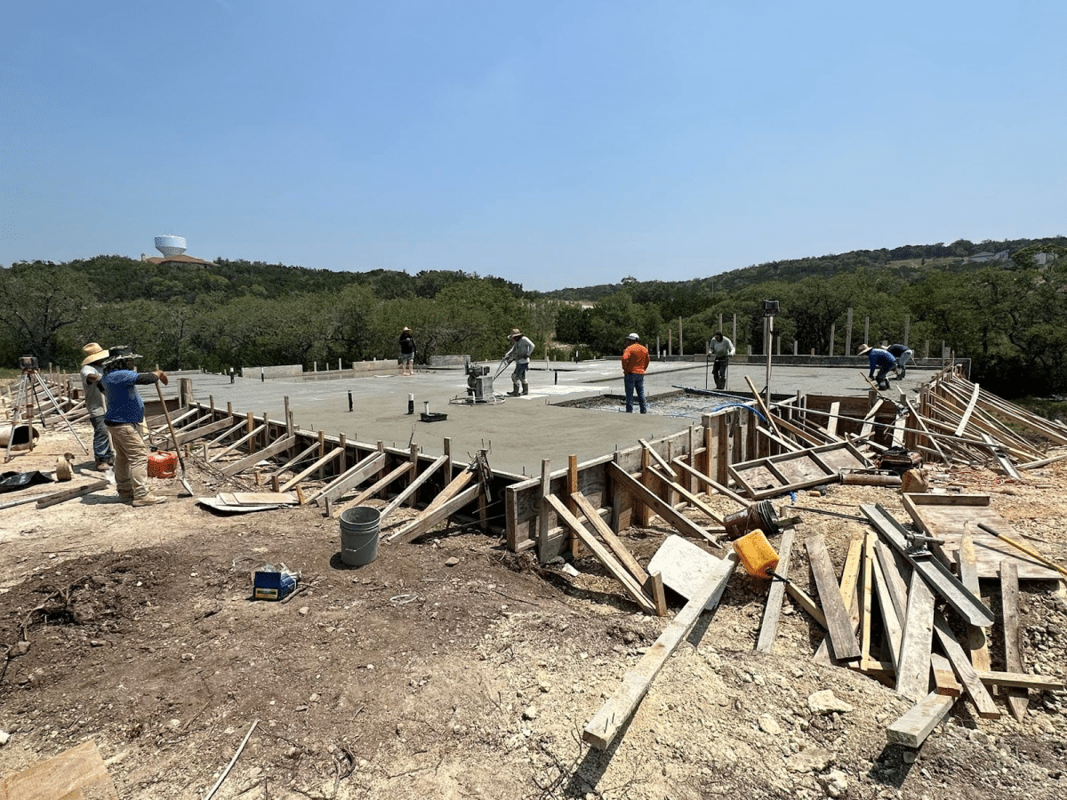 A group of people working on a construction site, with tools and materials scattered around.