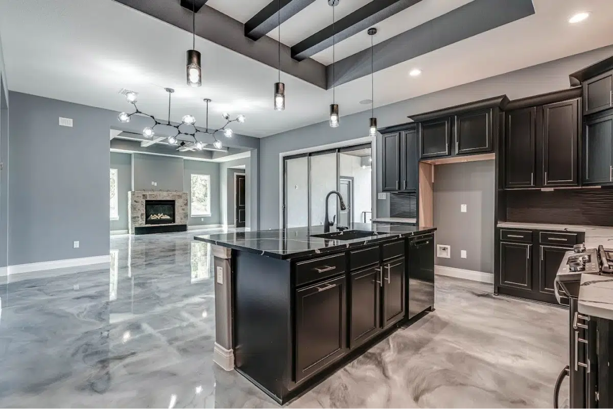 A modern kitchen with black cabinets, a large island, and a metallic floor.