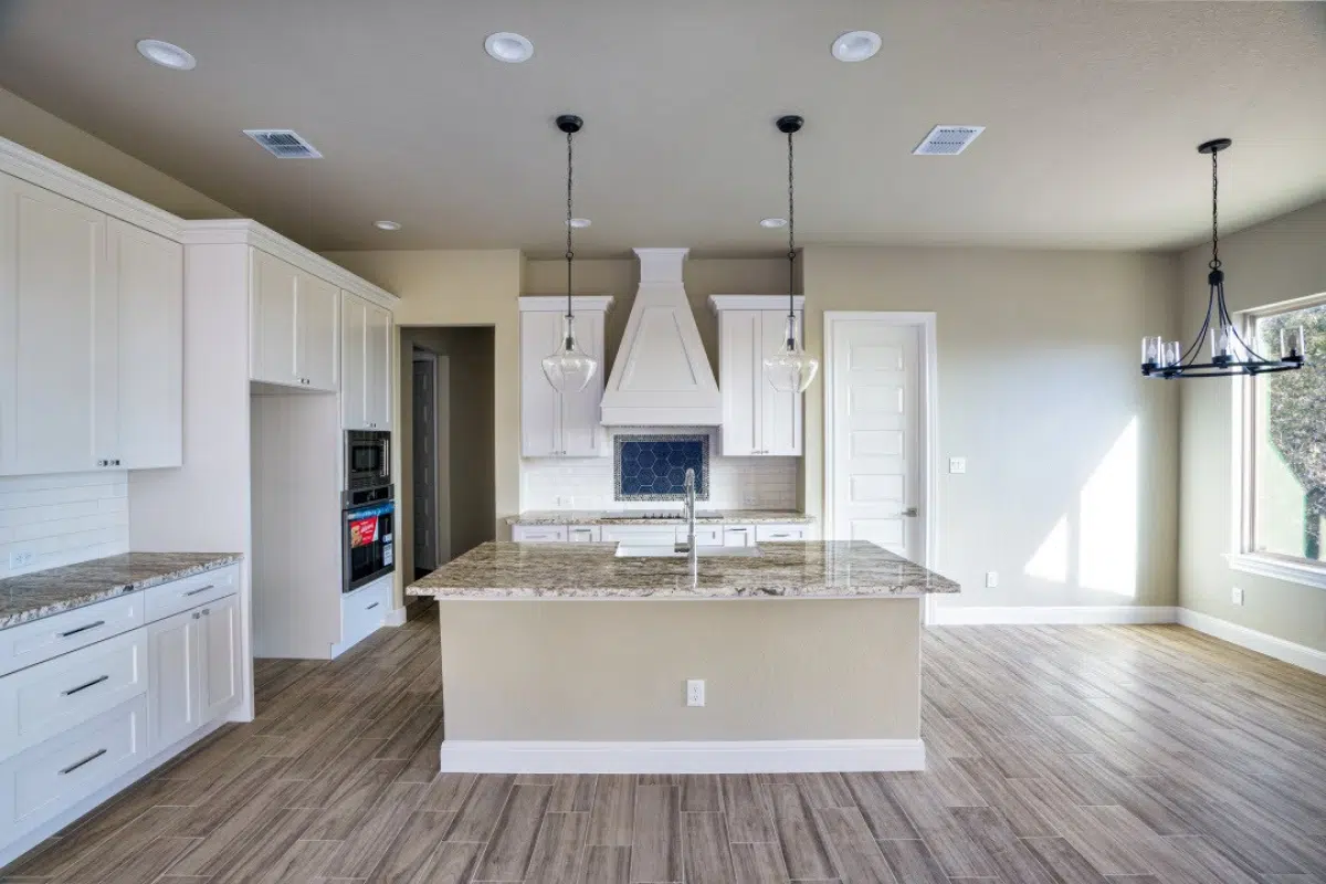 A spacious kitchen with white cabinets, granite countertops, and a large island.