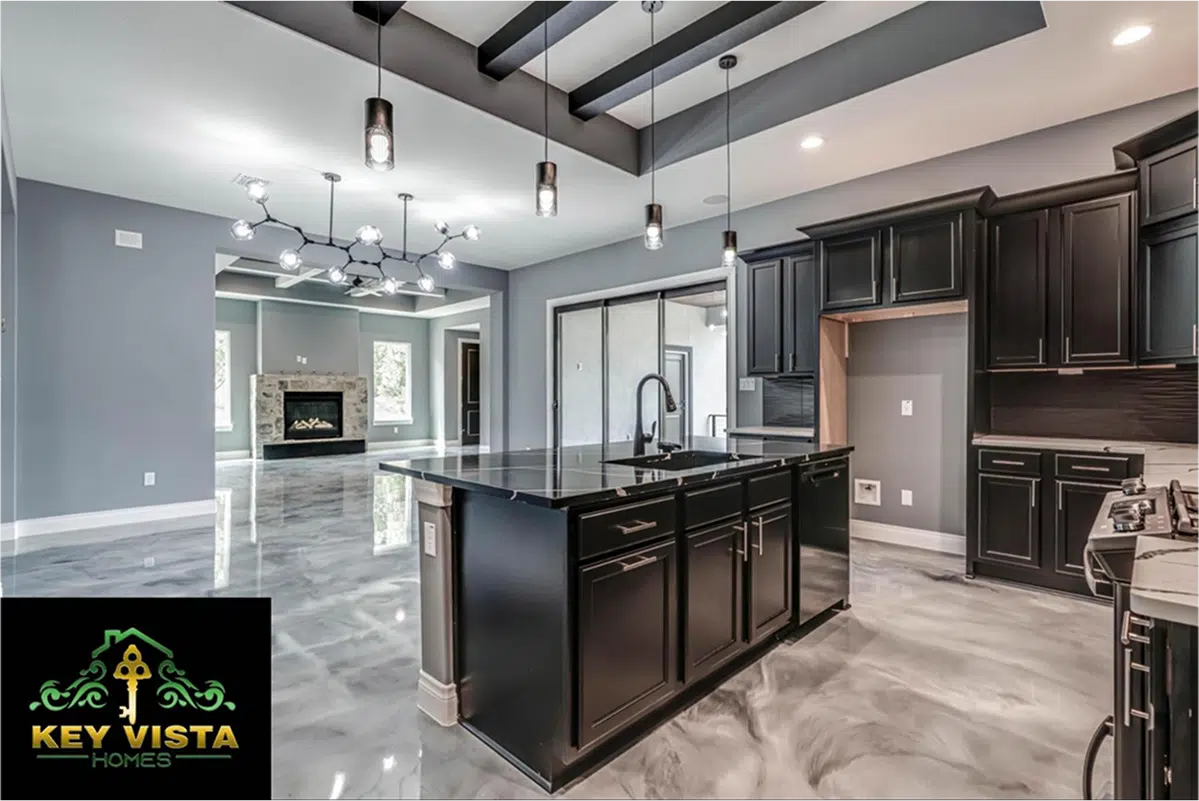 Modern kitchen with black cabinets, island, chandelier, Key Vista Homes logo.