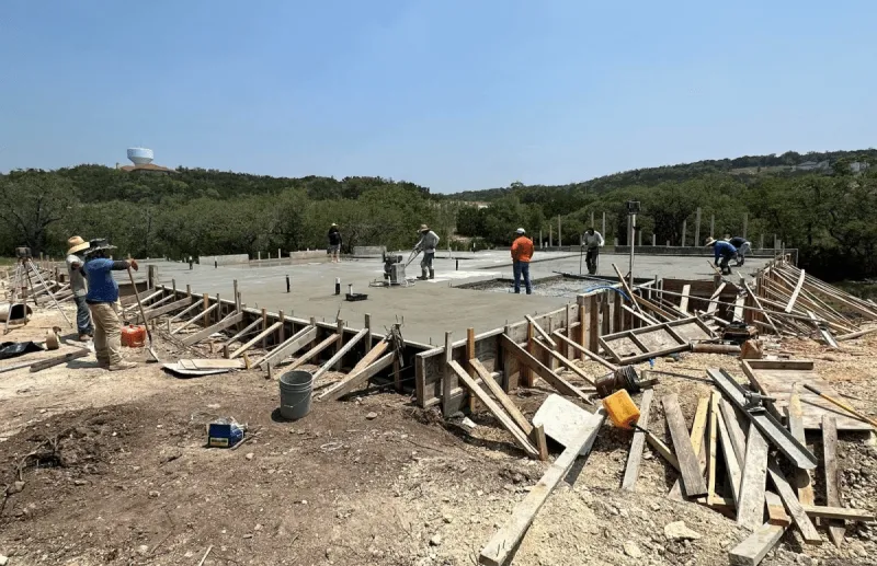 A group of people working on a construction site, with tools and materials scattered around.