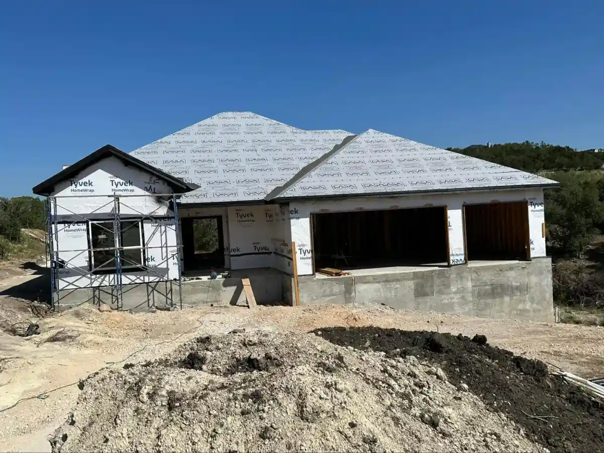 A partially constructed home wrapped in protective material, revealing open windows and doorways.