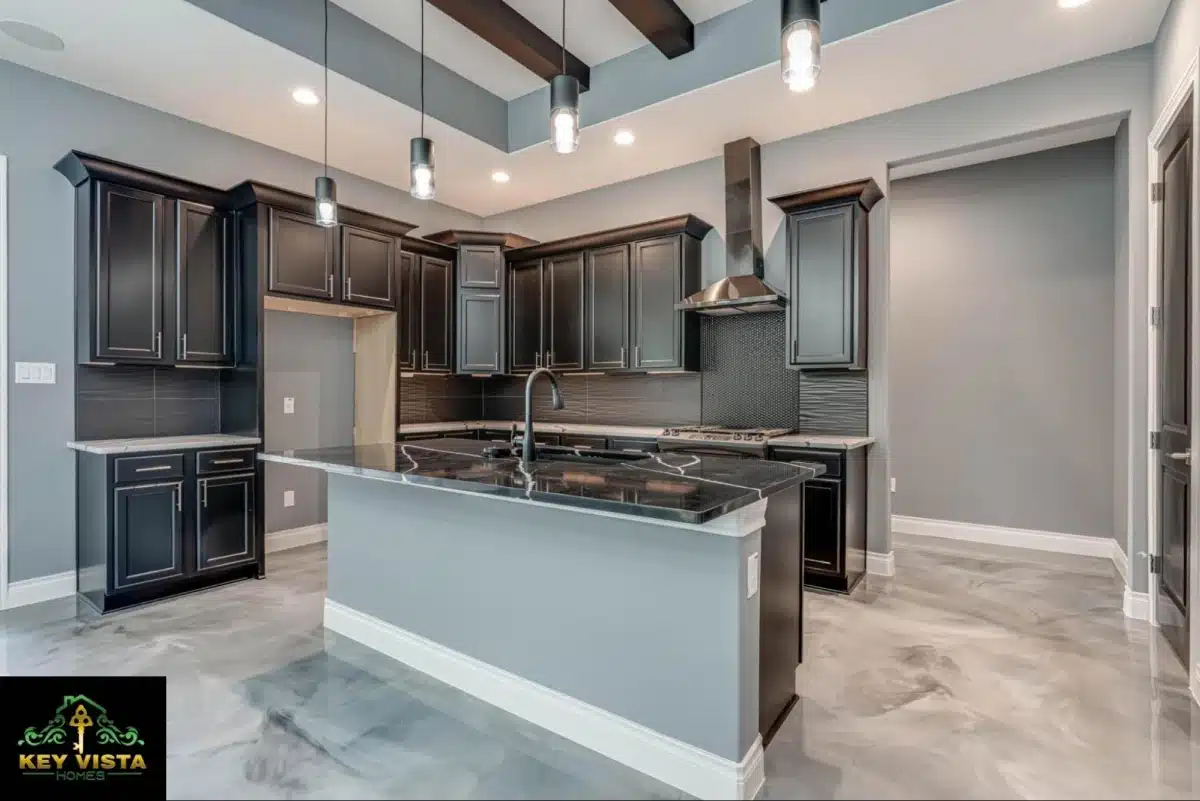 A sleek, contemporary kitchen with black cabinetry, a dark central island, stainless-steel hood vent, pendant lighting, and a glossy, gray epoxy floor.