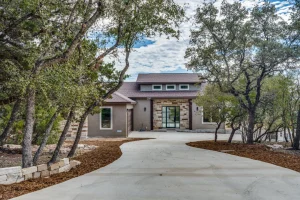 Contemporary house with stone entrance and tree-lined driveway.