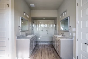 Dual vanity bathroom with granite counters and glass-enclosed shower.