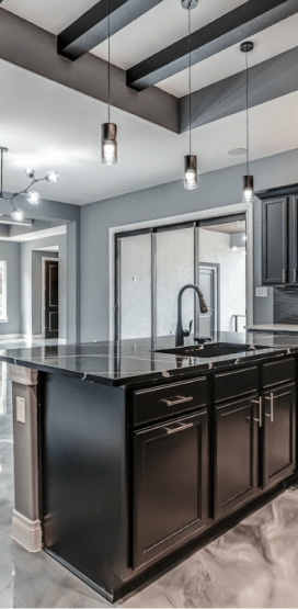 Modern Home Builder in Boerne, TX 6 A modern kitchen with black cabinets, a large island, and a metallic floor.