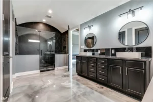 Luxurious bathroom with dual vanity, round mirrors, hexagonal tile shower, and glossy floor.