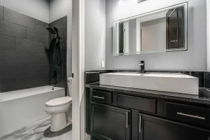 Modern bathroom with black vanity and tub.